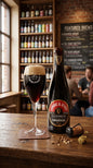 Dunkles Timmermans Lambic Stout Bier in Flasche mit Glas, Holztheke und Regal im Hintergrund.