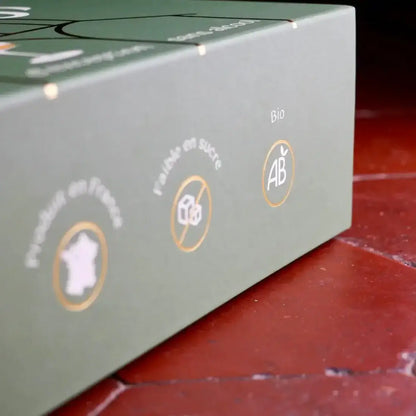 Grüne Geschenkbox mit weißen und orangen Trink- und Herkunftssymbolen auf rotem Untergrund.